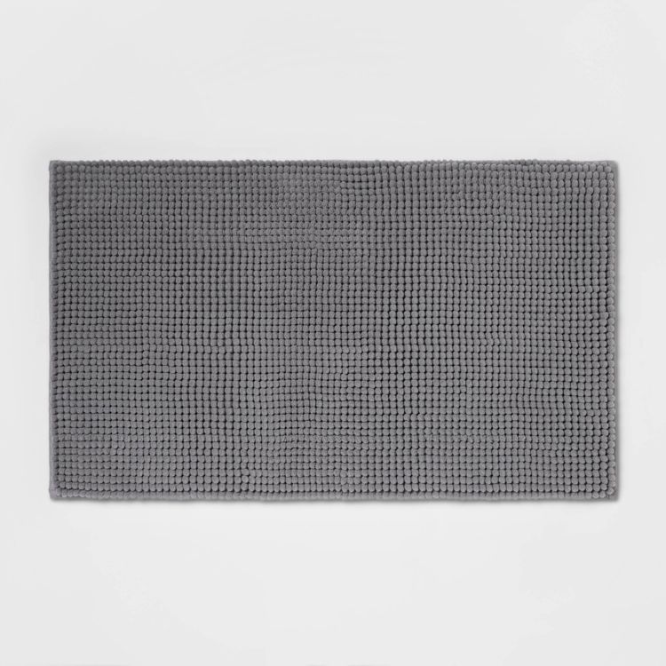 A rectangular gray colored bath mat with a textured, waffle-like pattern.