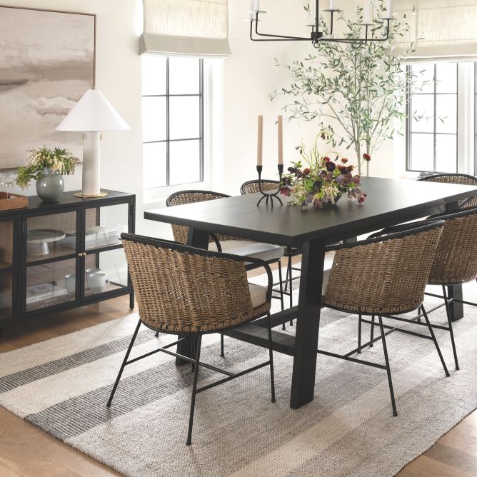 Black dining table with wicker dining chairs and glass sideboard