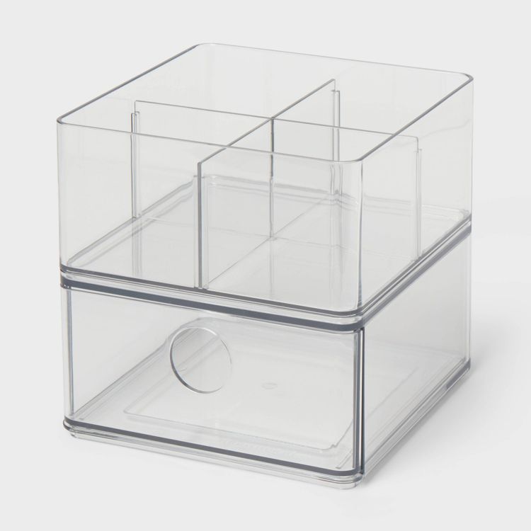 Clear plastic storage container with multiple compartments and a drawer featuring a circular handle.