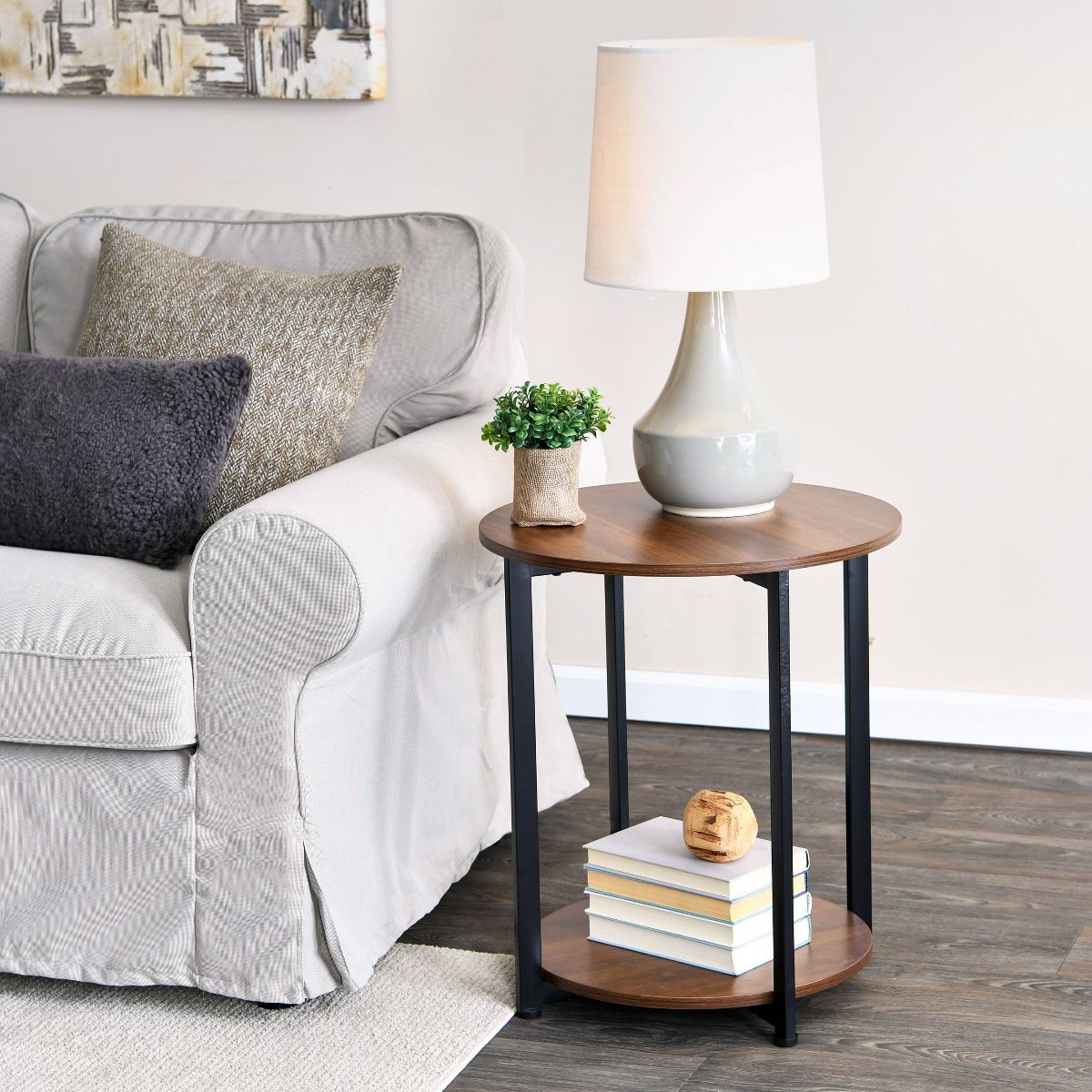 Round dark wood end table with black metal legs and lower shelf