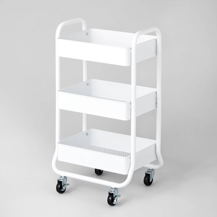 A white colored utility storage cart with three shelves and four wheels.