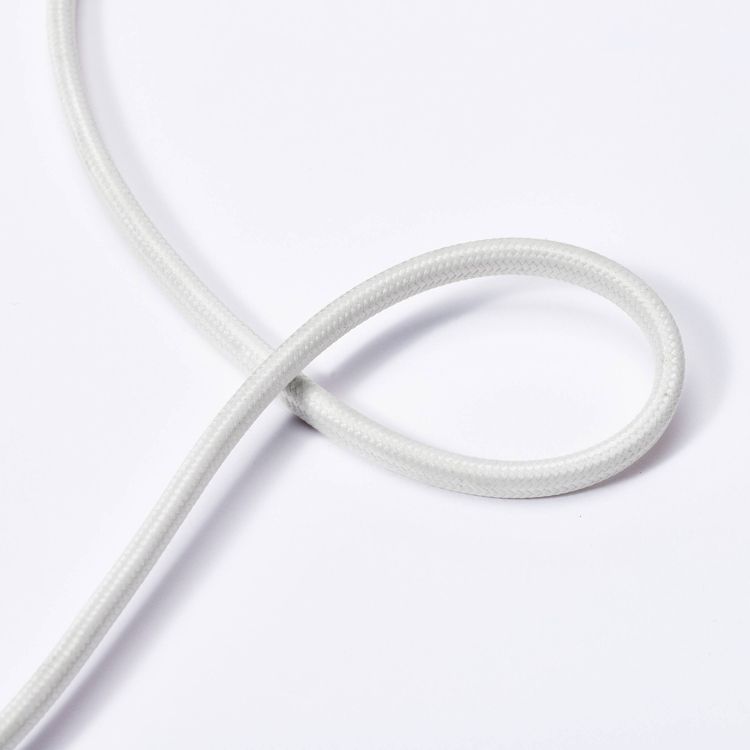 A white colored braided electrical cord looped on a white surface.