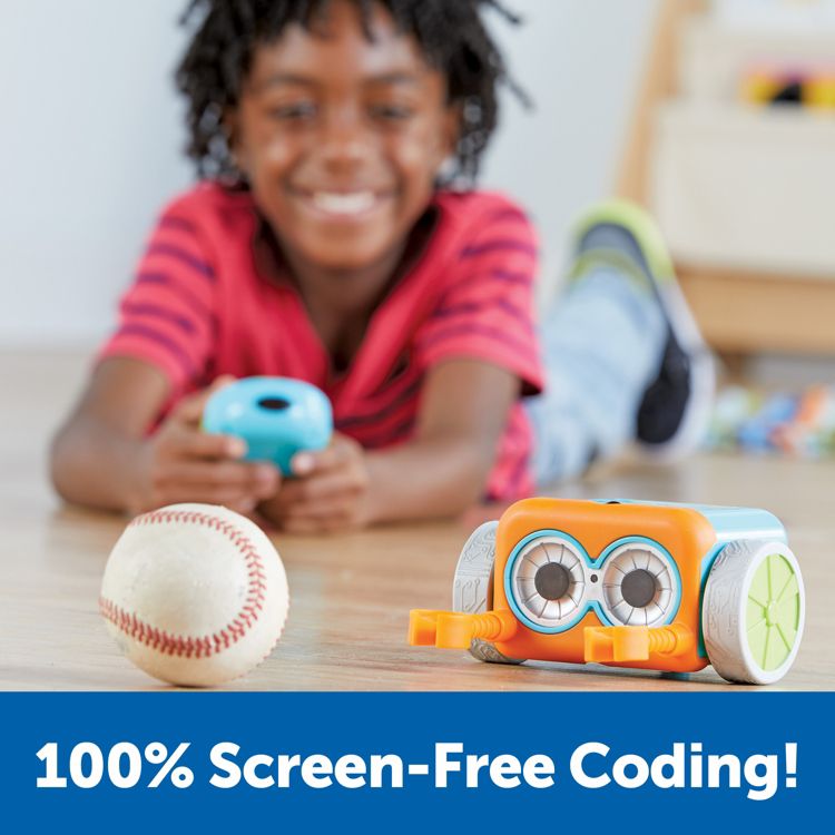 An orange and blue colored robot toy with wheels is placed on the floor next to a baseball, with the text "100% Screen-Free Coding!" displayed below.