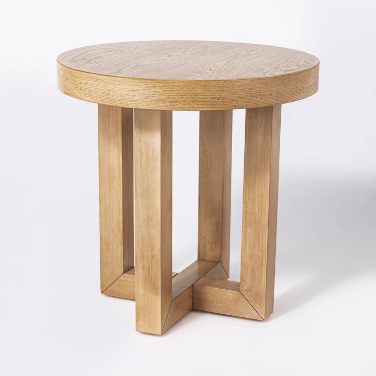 Round wooden table with a thick top and four vertical legs connected at the base.