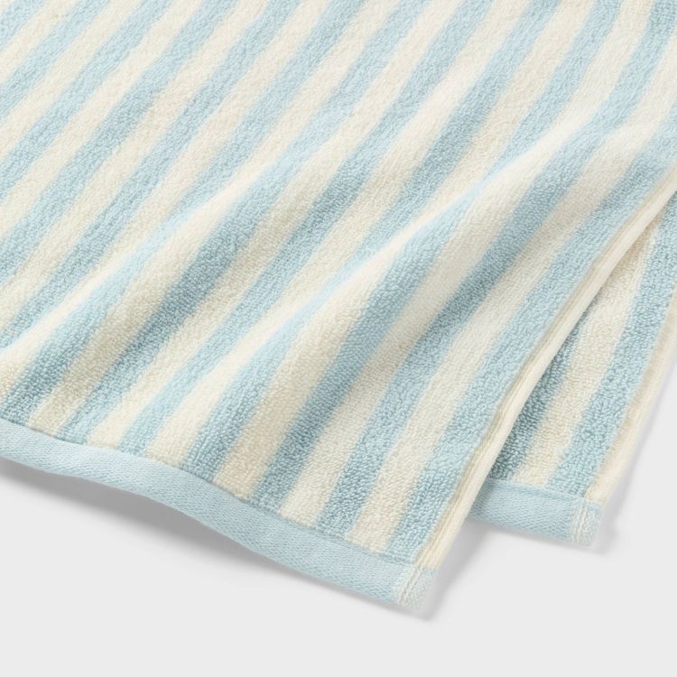 A towel with light blue and white colored stripes, folded at the edges.