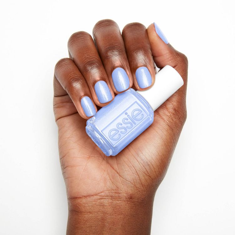 Hand holding a bottle of light blue colored nail polish with matching painted nails.
