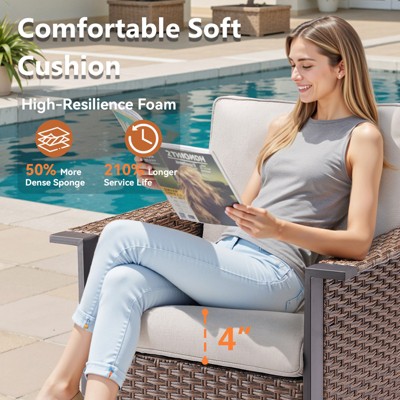 Person sitting on wicker patio chair with beige cushion by pool