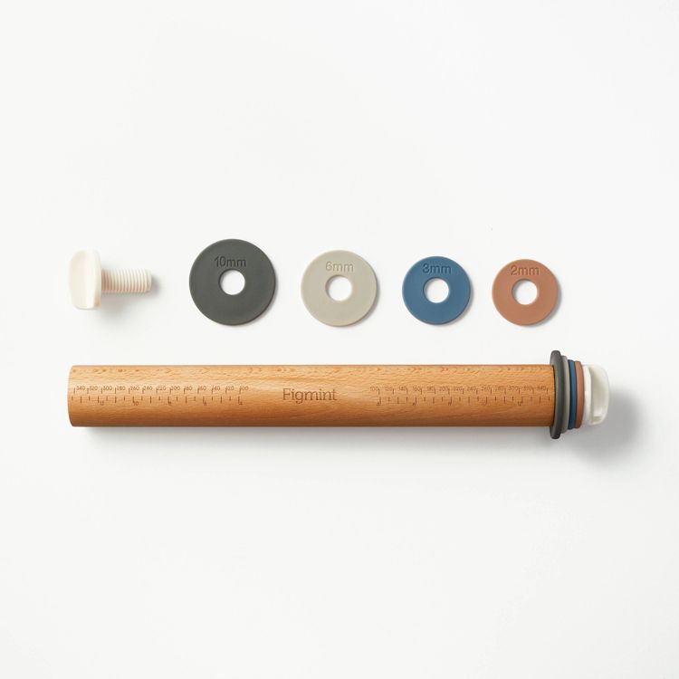 A wooden rolling pin with measurement markings, accompanied by four colored thickness rings labeled 10mm, 6mm, 3mm, and 2mm, and a white screw.