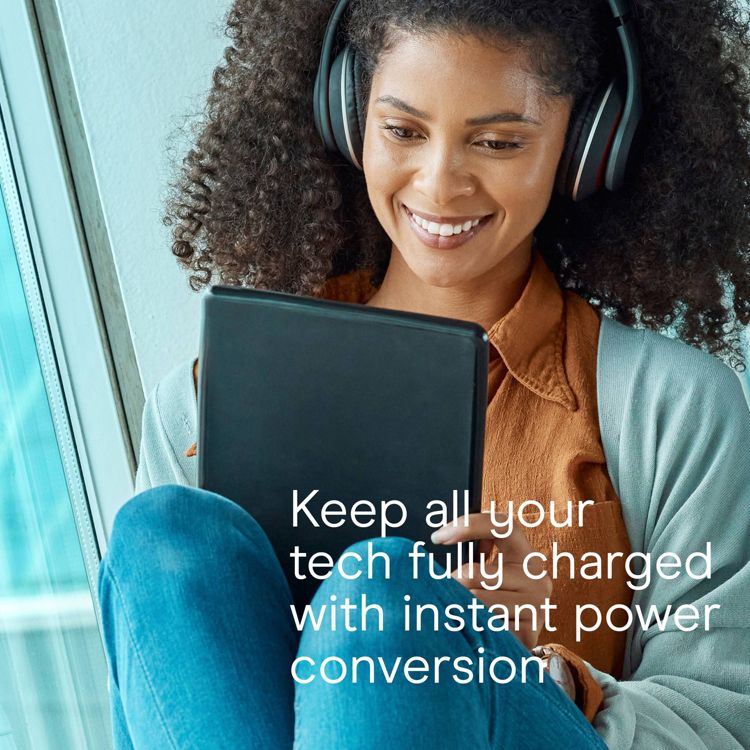 A person wearing headphones is holding a tablet with the text "Keep all your tech fully charged with instant power conversion" displayed.