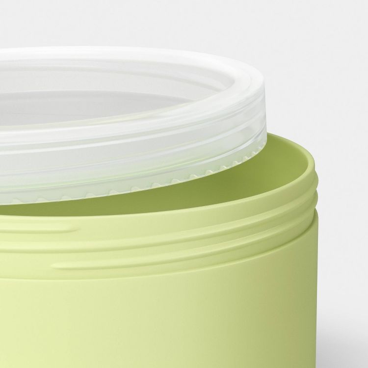 A light green colored container with a partially open clear lid.