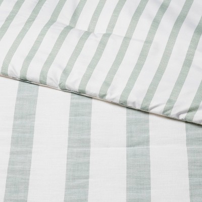 White and light green colored striped bedding with a quilted texture.