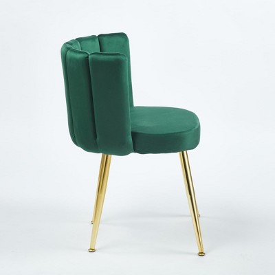 Side angle view of green velvet dining chair with gold legs.