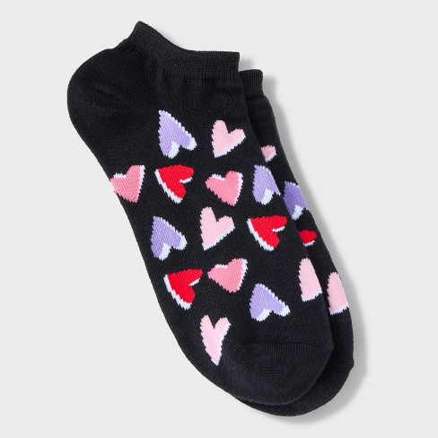Cropped view of beautiful female legs in black ankle socks with red heart  prints. The young