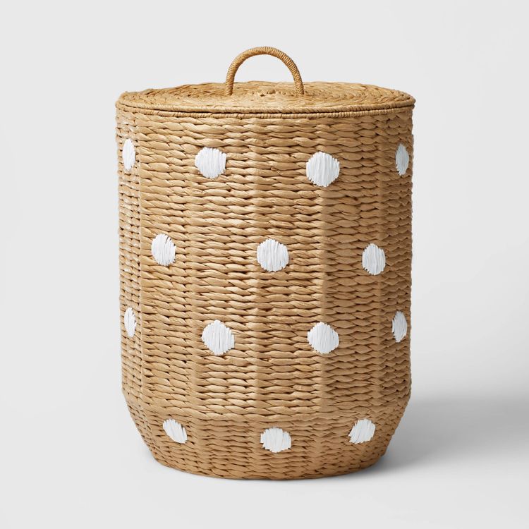 A woven hamper with a lid, featuring a natural colored base and white colored polka dots.