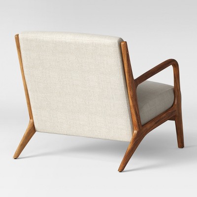 A chair with a light beige colored fabric backrest and seat, featuring a wooden frame and armrests.