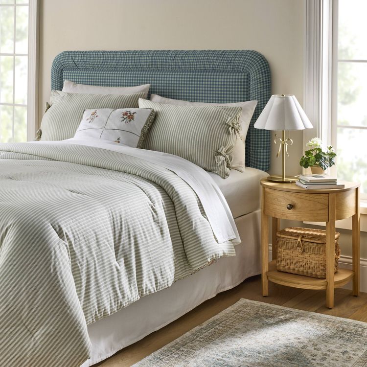 A blue and white checkered headboard is positioned behind a bed with striped bedding and decorative pillows.