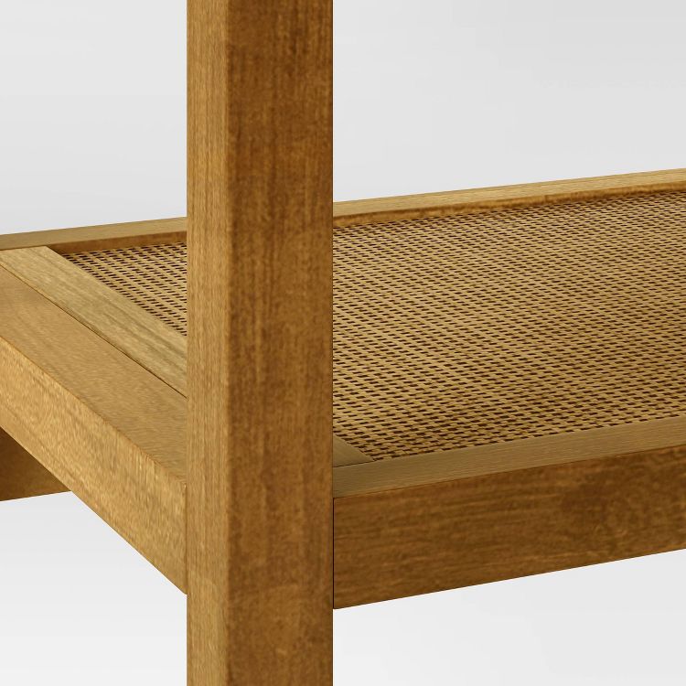 A close-up of a wooden table with a woven rattan shelf.