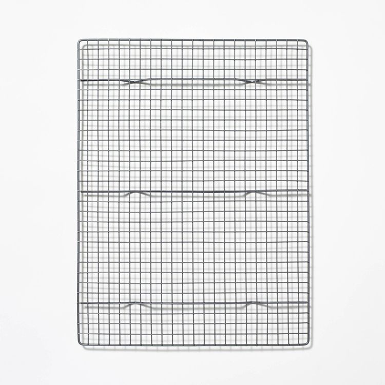 A rectangular metal cooling rack with a grid pattern placed on a white background.