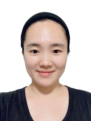 Headshot of Rankyung Park, a woman with light brown skin, black hair tied up, wearing black hairband and black shirt, photographed again a white background.
