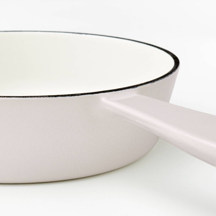 A light pink colored skillet with a long handle and white interior.