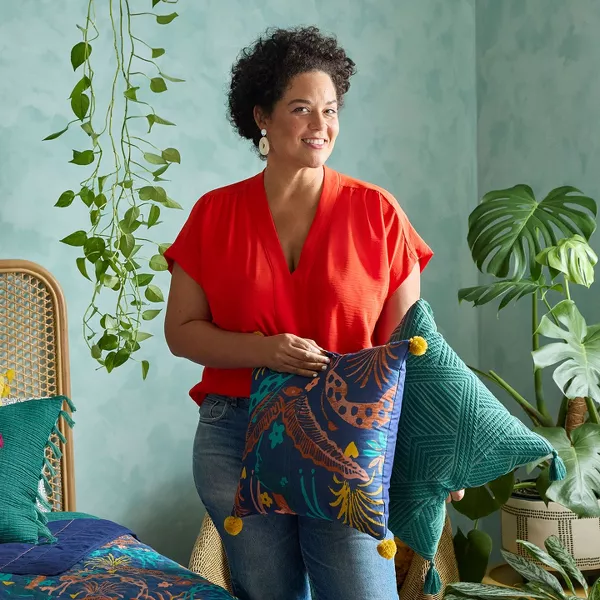 Justina holding throw pillows next to a bed