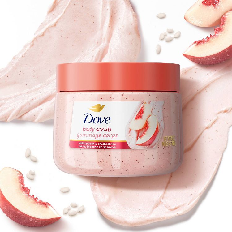 Dove Body Scrub with white peach and crushed rice. The jar is peach-colored with a matching lid, set against a backdrop of creamy scrub texture and fresh peach slices. Gentle exfoliation for radiant skin. 