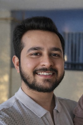 Headshot of Diraj Shankar, man with medium brown skin and short, dark black hair, wearing a light grey polo shirt with a subtle dotted pattern, smiling at the camera.