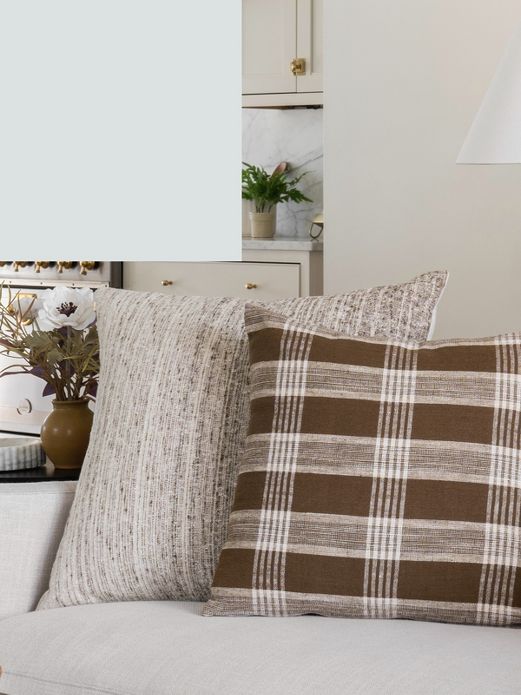 Tan textured throw pillow and plaid throw pillows on couch.