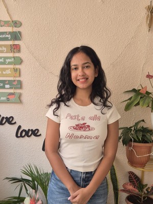 headshot of prashasti gupta, a woman with medium skin tone and black hair, wearing white T-shirt, photographed against a beige background