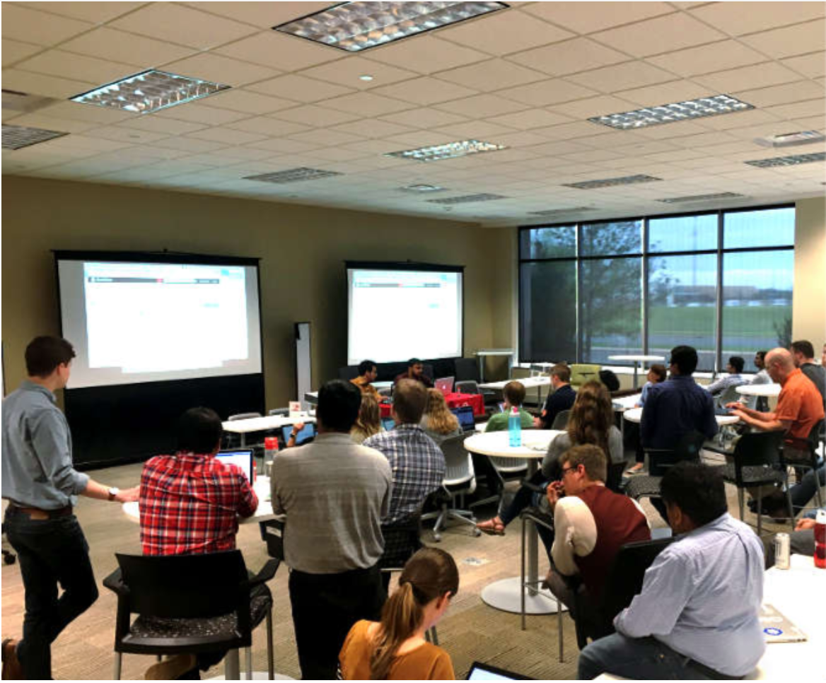 technology coaching session at Target HQ, with a group of technologists in a conference room, looking up at two screens. The people are all pictured from the back.