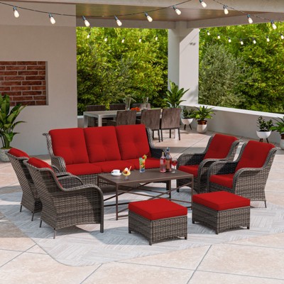 Red-cushioned wicker outdoor furniture with string lights overhead
