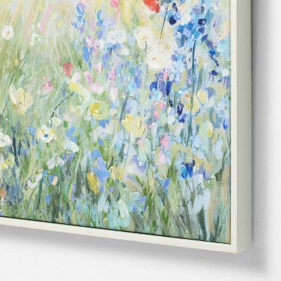 A framed painting depicting an abstract field of flowers in various pastel colors, including blue, pink, yellow, and white.