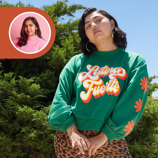 [lang=es]Una joven adulta de pie parada con orgullo al aire libre. Lleva una sudadera verde con flores naranja en las mangas y texto ilustrado en la parte delantera de la sudadera que dice: "Latina Fuerte".[/lang]