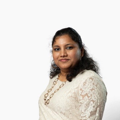 Headshot of Jayanthi Narayanan. Smiling woman with light brown skin tone, wearing a golden colored necklace and cream top.