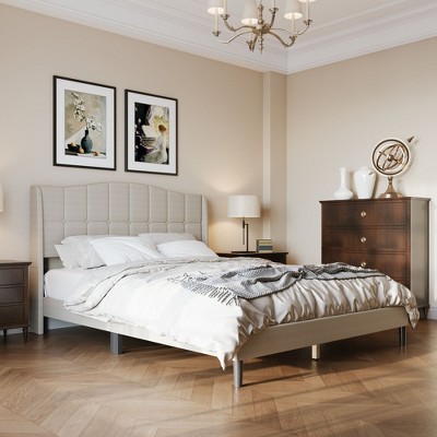 Beige upholstered bed in a classic-inspired bedroom with beige walls, chandelier, and dresser