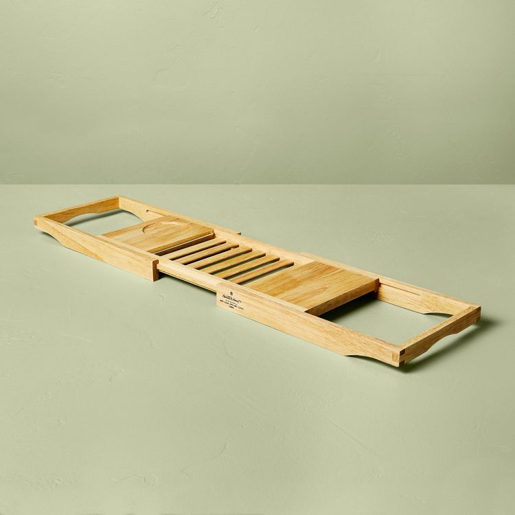 A light brown colored wooden tray with slatted sections and a circular cutout, placed on a light green surface.