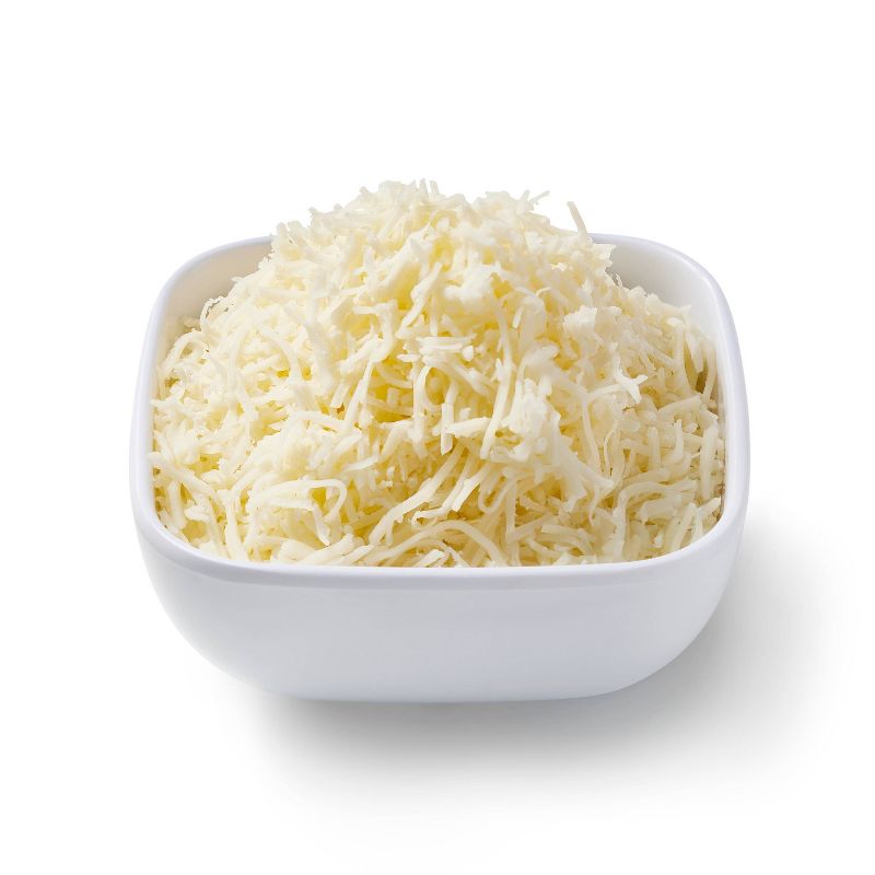 A white bowl filled with shredded white colored cheese.