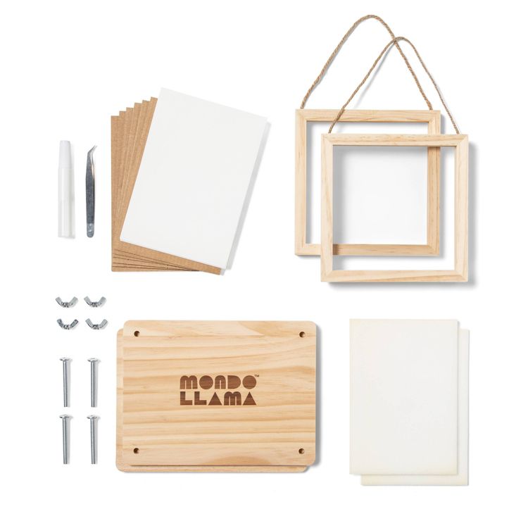 Art kit including two wooden frames with string, a wooden board with "Mondo Llama" text, white and brown sheets, a pair of tweezers, a white pen, screws, and wing nuts.