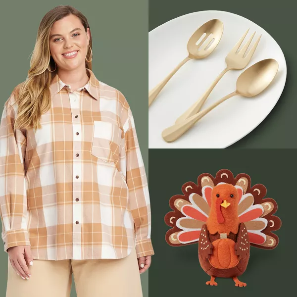 A dinner table with a platter of sliced turkey, garnished with pomegranate and small apples, is in the center. Surrounding it are mashed potatoes, green beans, a basket of bread, and drinks. The tablecloth is a soft brown color.