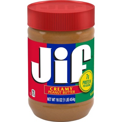 An opened jar of peanut butter with a small spoon Stock Photo