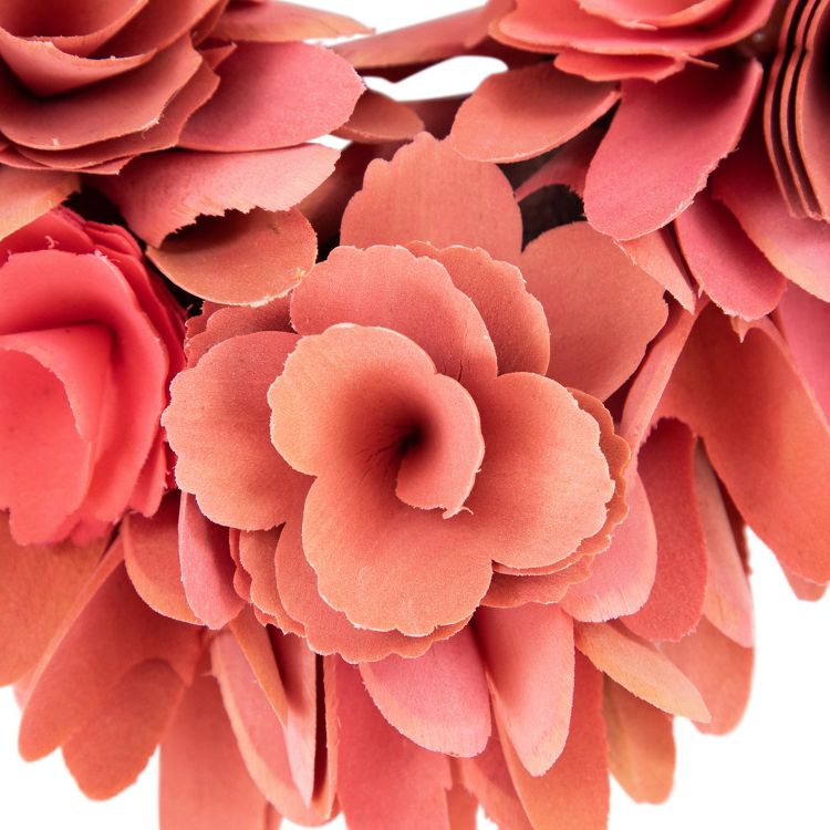 A wreath made of layered, coral colored paper flowers.