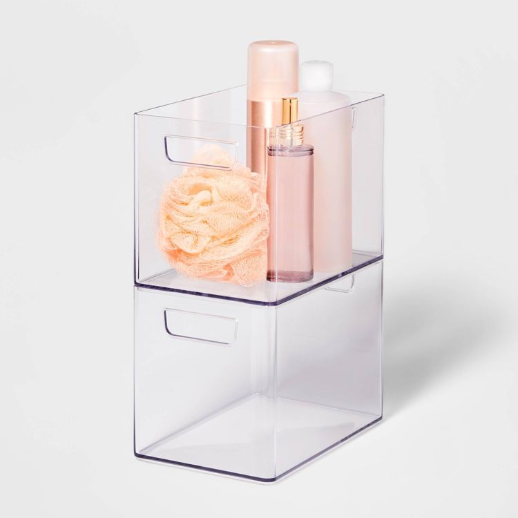 Clear bathroom organizer bin with handles, containing a peach-colored bath sponge and two bottles.