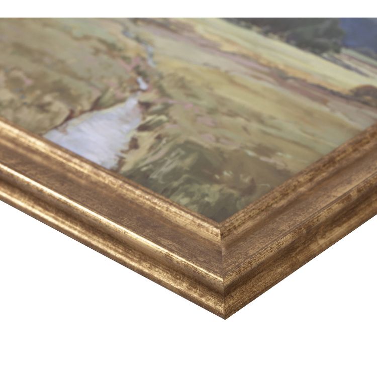 A close-up of a landscape painting with a gold colored frame, showing a river running through a grassy field.