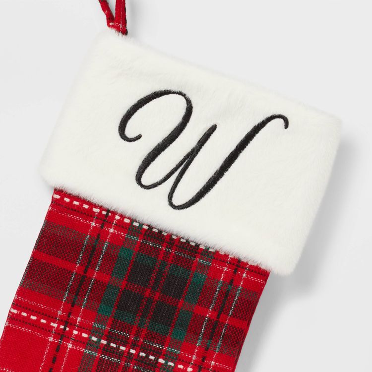 A red and green plaid colored stocking with a white cuff featuring a black letter "W" embroidered on it.