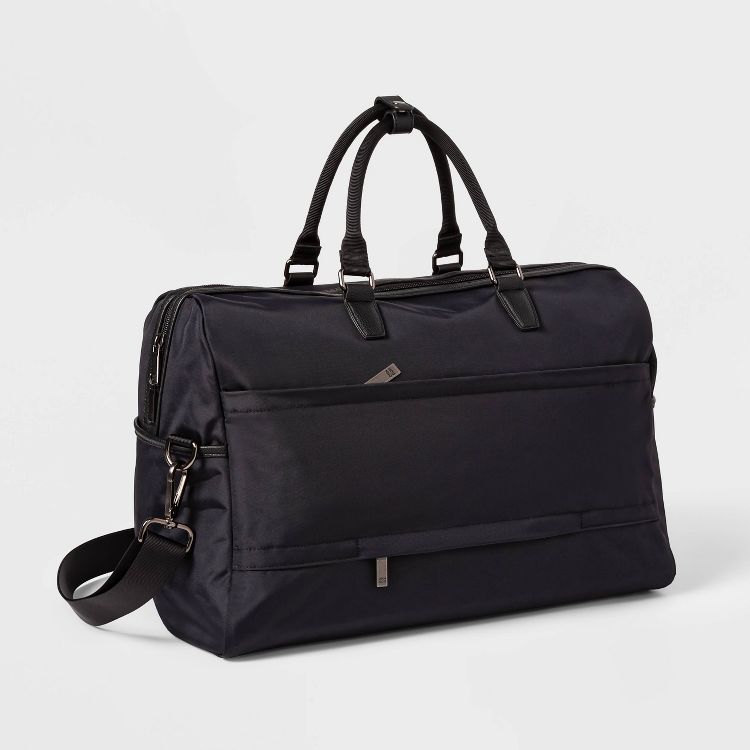 A black colored duffel bag with dual handles and an adjustable shoulder strap.