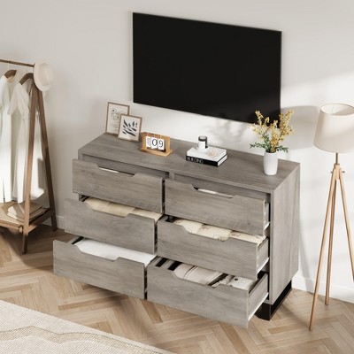 Two gray dressers with many open drawers and a TV mounted above