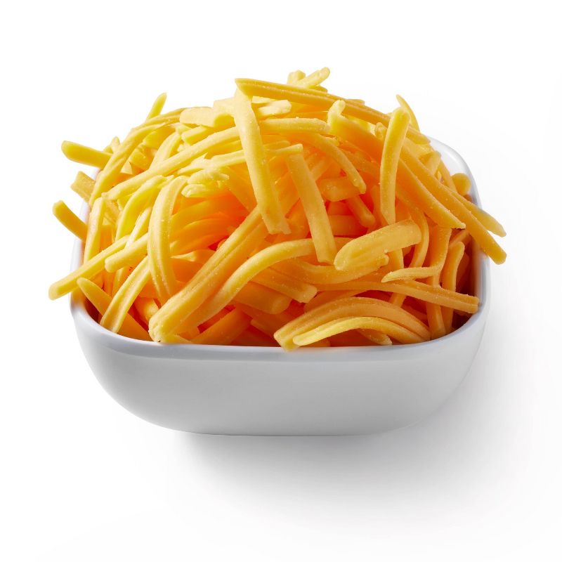 A white bowl filled with shredded yellow colored cheese.
