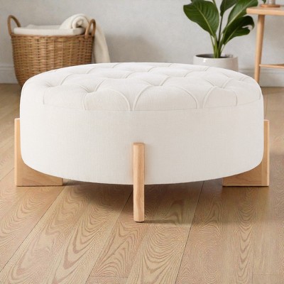 White round tufted ottoman with wooden legs on wooden floor