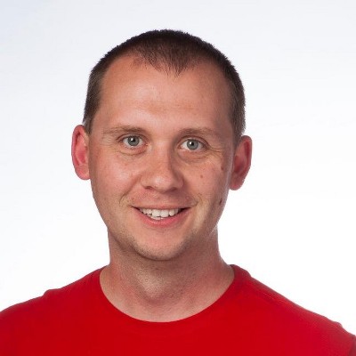 Head shot of Jay Kline, a man with pale skin, very short brown hair, wearing a red t-shirt.