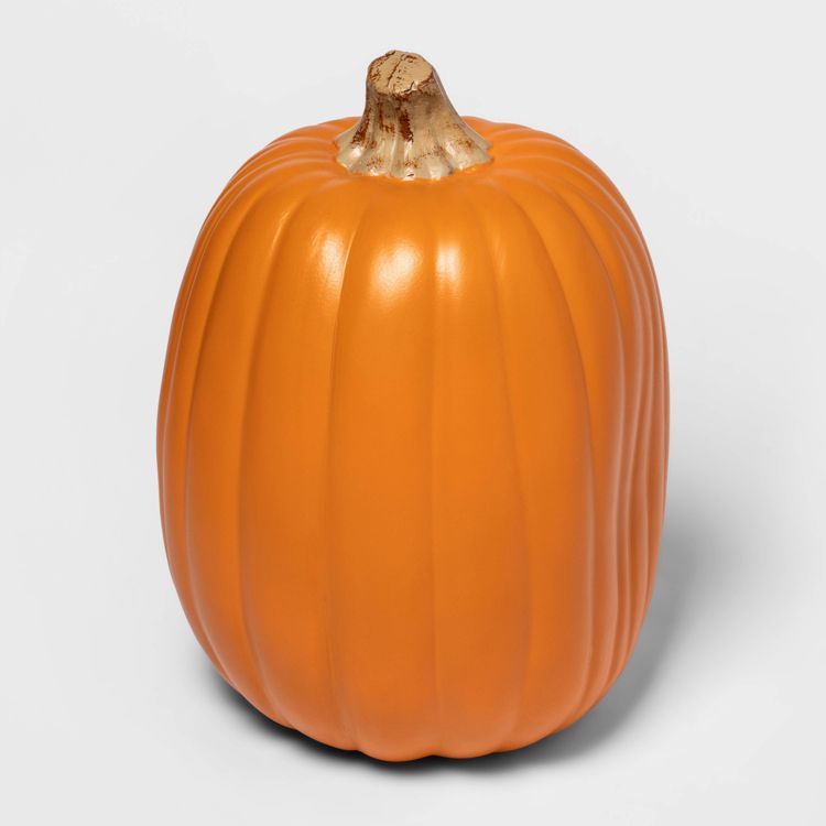 A large orange colored pumpkin with a light brown stem on a plain background.